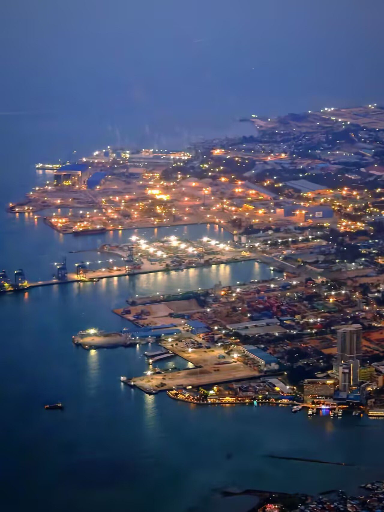 夜色中从飞机舷窗俯瞰新加坡港口和海岸灯光
